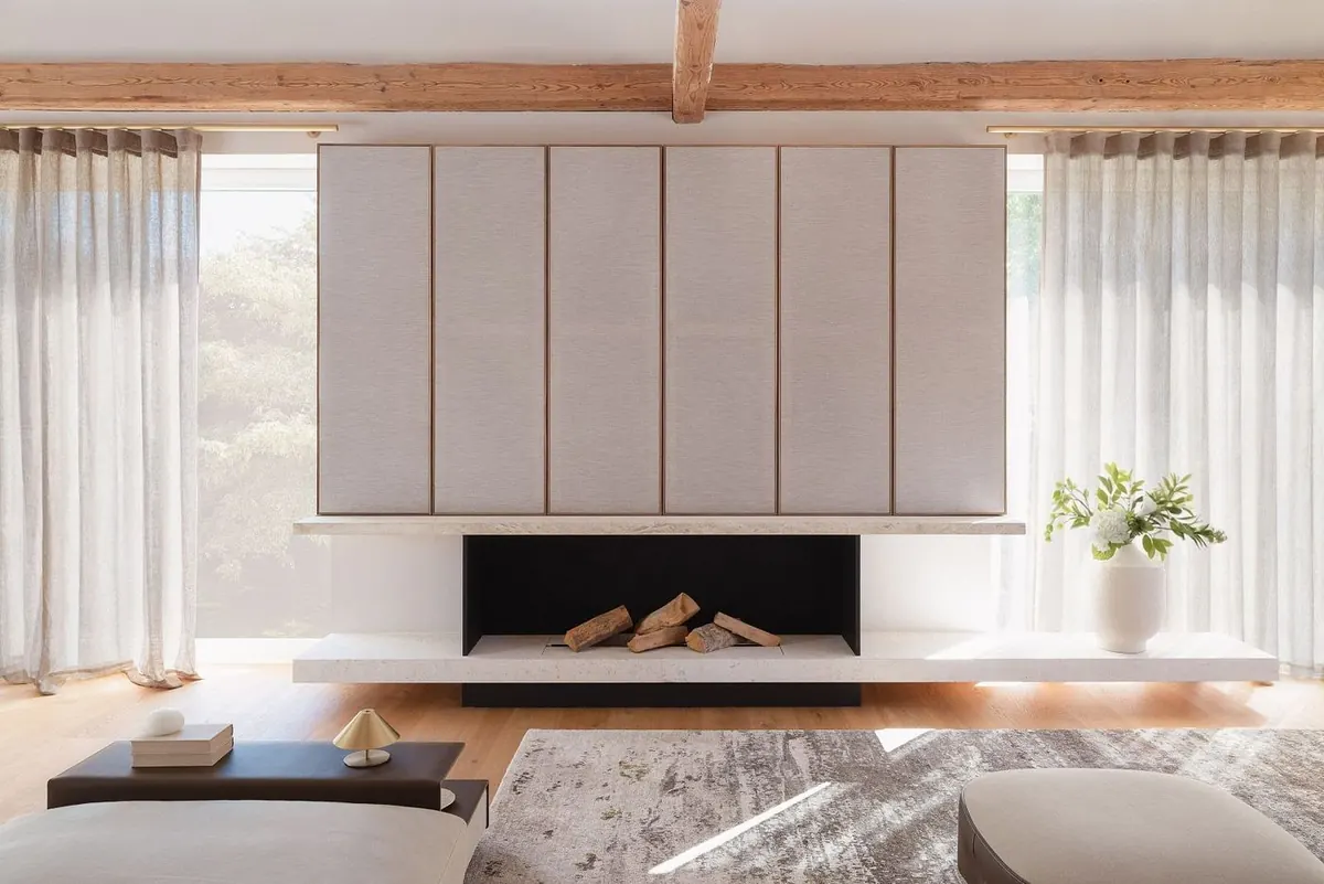 Kamin, stoffbespannte Wand und alte Balken im Wohnzimmer-Loft.