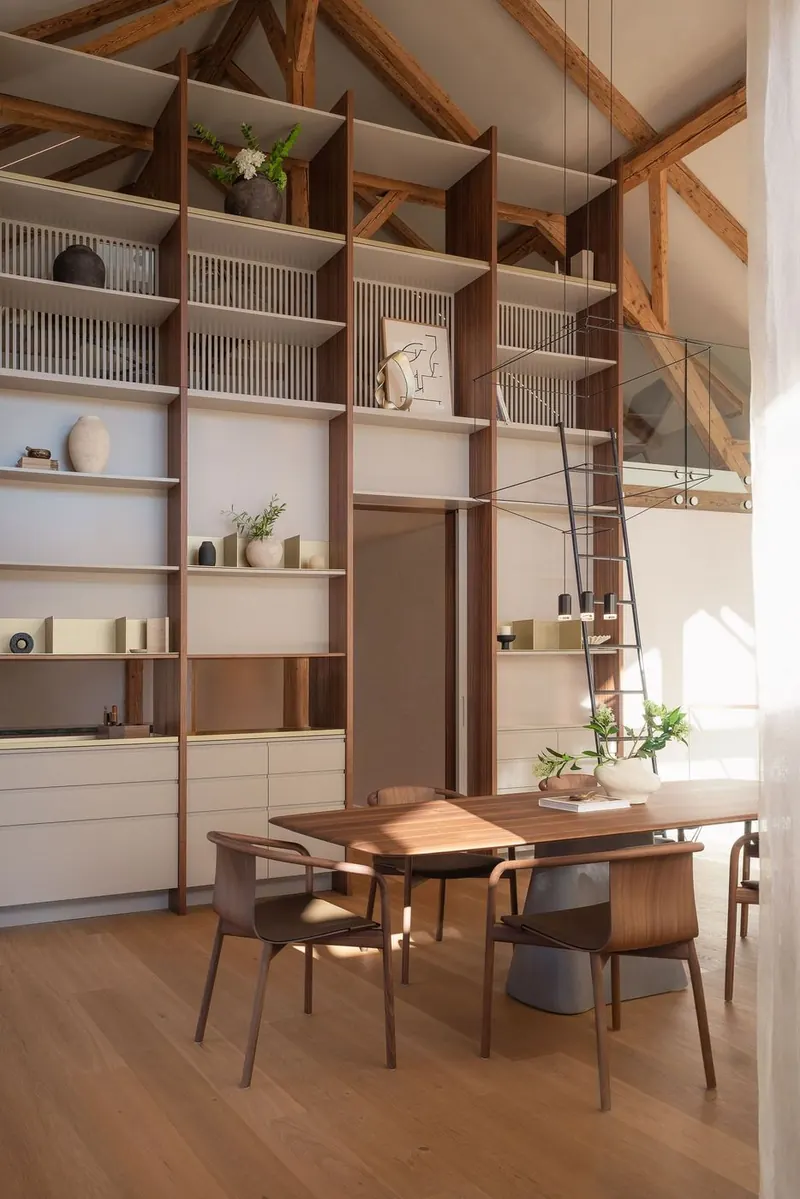 Die raumhohe Regalwand aus Nussbaum mit Leiter im Wohnzimmer-Loft.