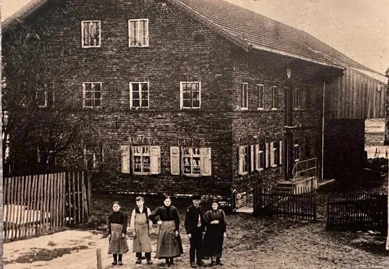 Historische Aufnahme des Bauernhofs mit mehreren Generationen der Familie vor dem Haus.