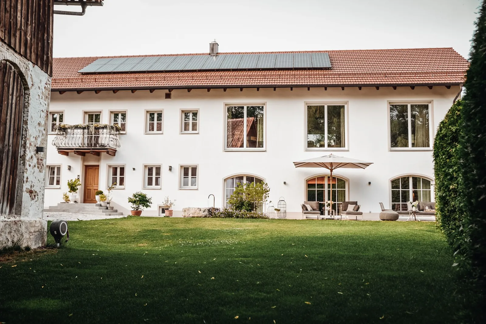 Der Innenhof: Rasen, die weiße Hoffassade mit Balkon und Bogenfenstern, Terrasse mit Sonnenschirm.