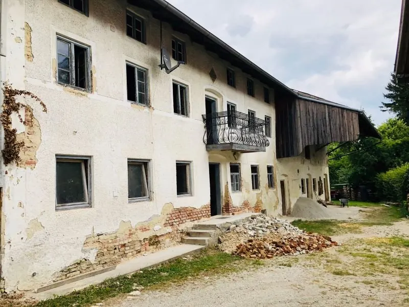 Die Hoffassade vor der Sanierung mit bröckelndem Putz, Balkon und Holzstadl.